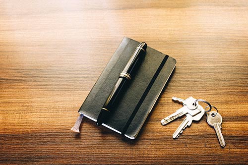 F�llfederhalter und Schl�ssel auf Notizbuch symbolisieren Hausverkauf, �bergabe